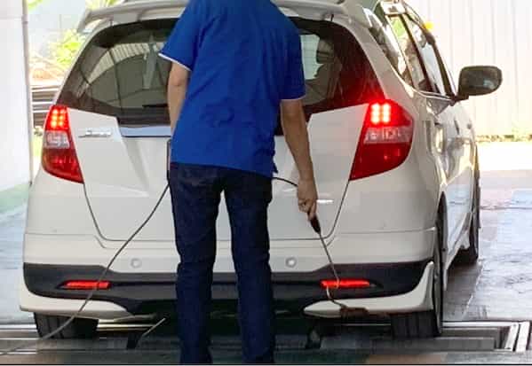 車の背部に検査器をあてて排気ガスのチェックをしているところ